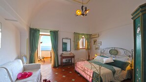 Un dormitorio con cama, una silla, una mesa y vista al mar.