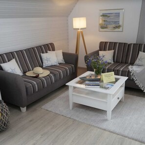 A cozy living room with striped sofas, a white coffee table, and a lamp.