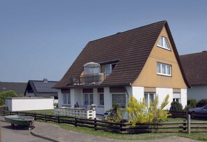 A two-story house with a sloped roof, a balcony, and a small attached garage.
