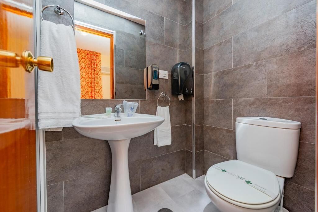 A bathroom with a pedestal sink, a toilet, and a shower area.