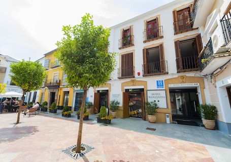 A hotel courtyard with outdoor seating, potted plants, and a tree.