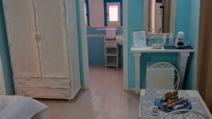 A room with a bed, a table with a chair, a wardrobe, a bathroom with a mirror, and a small table with snacks. - Bed and Breakfast Casa Tropea (Tropea)