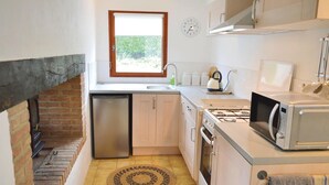 Une cuisine compacte équipée d’un lave-vaisselle intégré, d’une cuisinière, d’un four à micro-ondes et d’un évier.