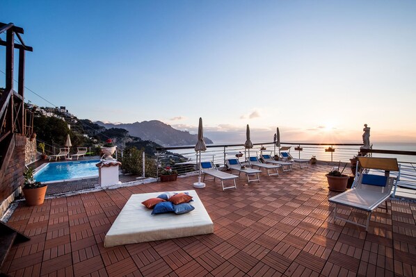 Une terrasse sur le toit avec une piscine, des chaises longues et une statue.