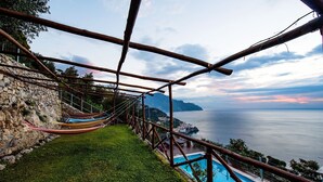 A wooden deck with a hammock and a pool overlooking a coastal view. - Villa Gioiello (Amalfi)