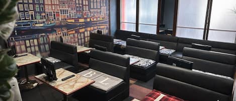 A restaurant with black leather booths, marble-topped tables, and a cityscape mural on the wall.