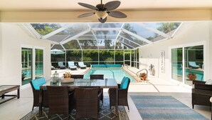 A covered outdoor area with a pool, dining table, and chairs. - Sunside House, 3/2 Pool Home in Gated Community and minutes from everything. (Naples)