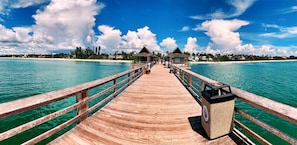 A wooden pier leading to overwater bungalows with clear turquoise water. - Sunside House, 3/2 Pool Home in Gated Community and minutes from everything. (Naples)