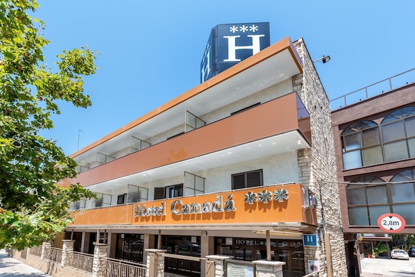 A hotel with a prominent 'Hotel Canada' sign, a 'H' on the building, and a height restriction sign of 2.8m.