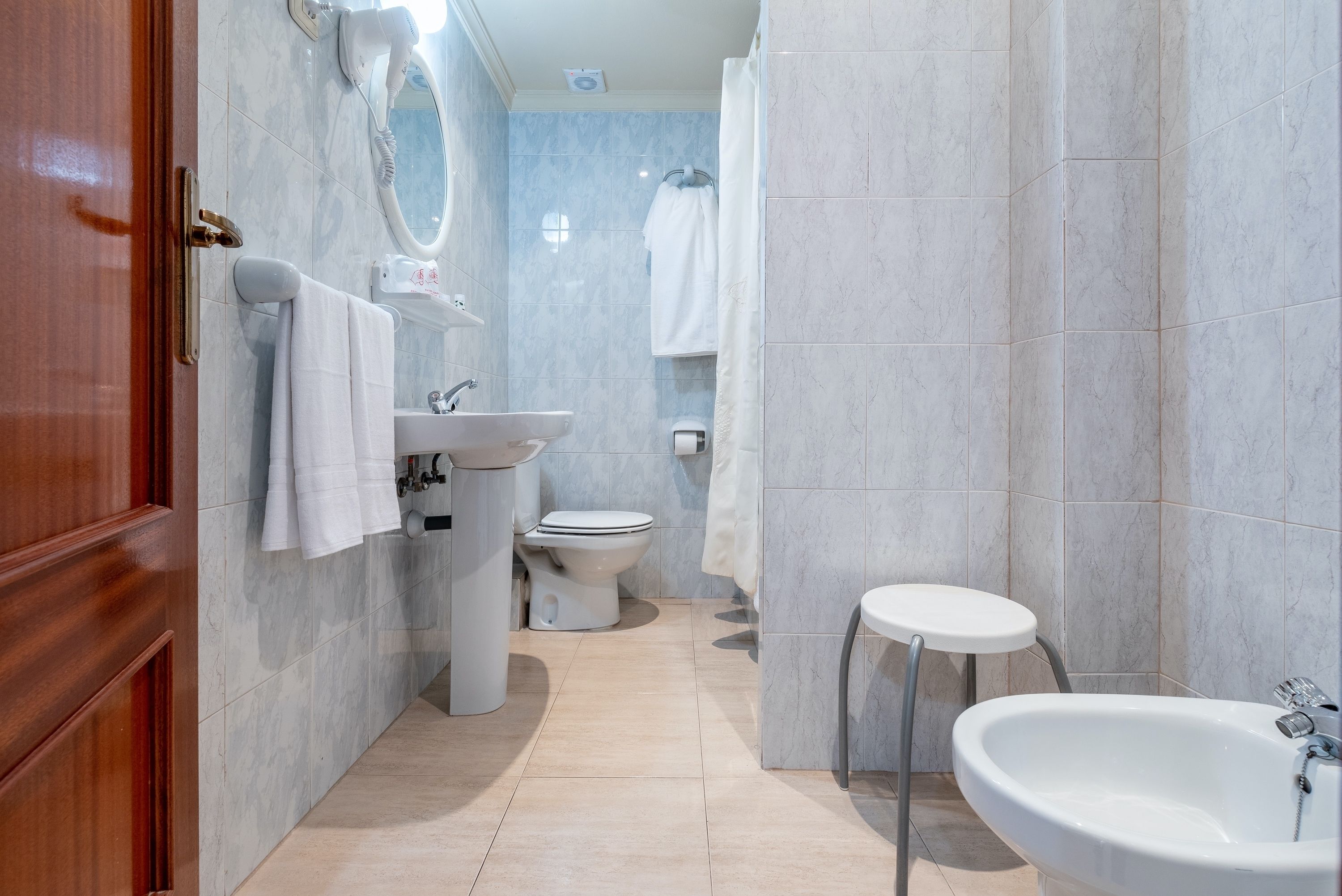 Un baño moderno con puerta de madera, lavamanos, inodoro y bidé.