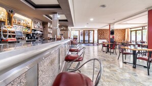 A restaurant with a bar area, seating, and a brick wall. - Hotel Canadá (Tarragona)