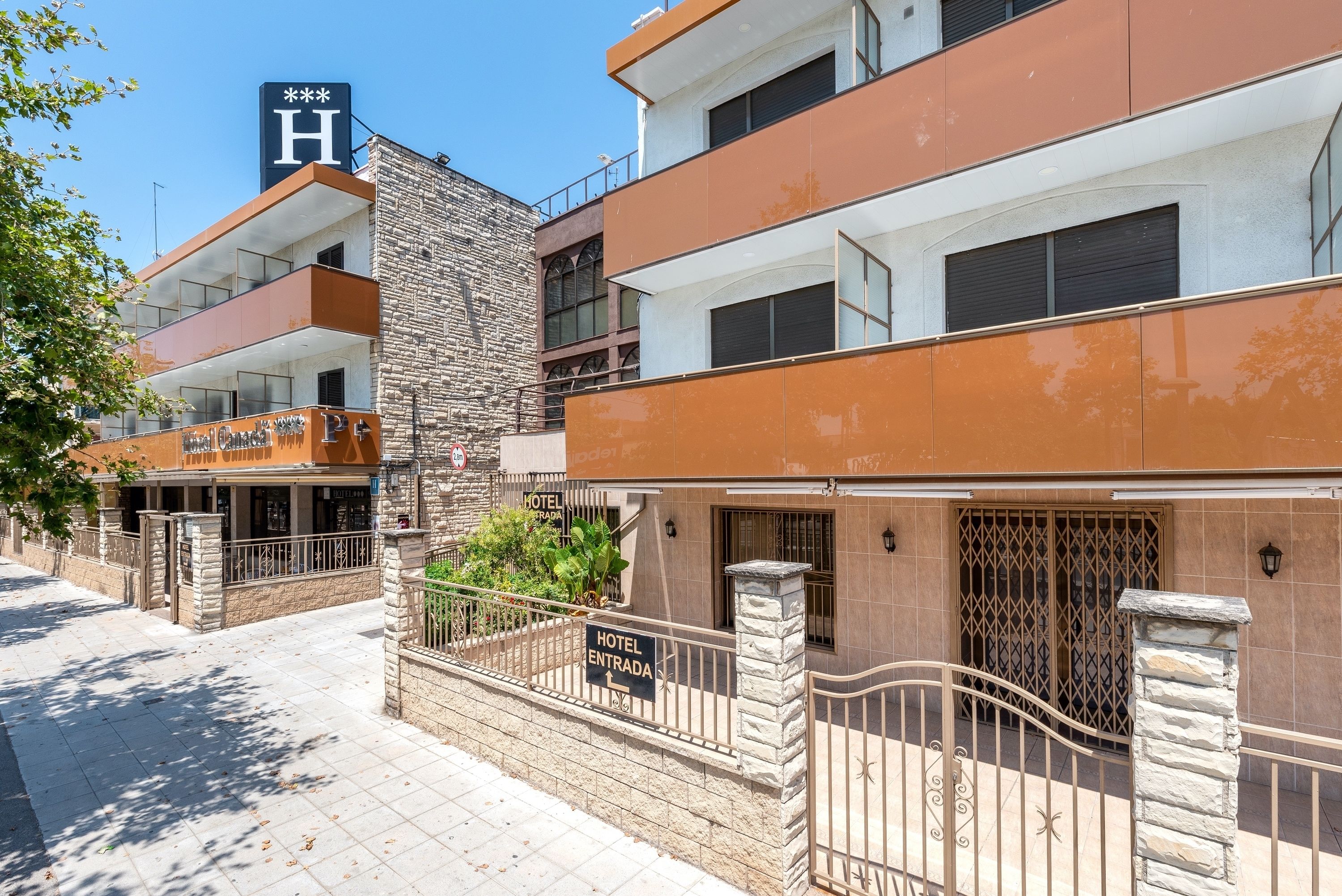 Un hotel con fachada de piedra, varios balcones y un letrero que indica la entrada.
