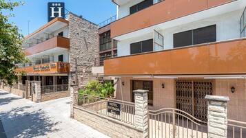 Un hotel con fachada de piedra, varios balcones y un letrero que indica la entrada.