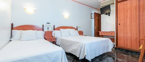 A hotel room with two single beds, a wooden wardrobe, a flat-screen TV, and a marble floor.