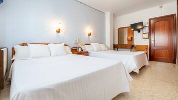 A hotel room with two beds, a desk, a chair, a TV, and a door.