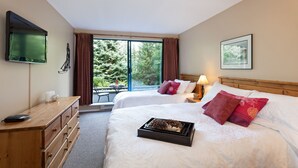 A hotel room with two beds, a TV, a desk, a chair, and a window with a view of trees. - Greystone #105, Renovated Ski in Ski out, sleeps 5, Free Wifi (105) (Whistler)