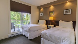 Een hotelkamer met twee bedden, een balkon en uitzicht op groen.