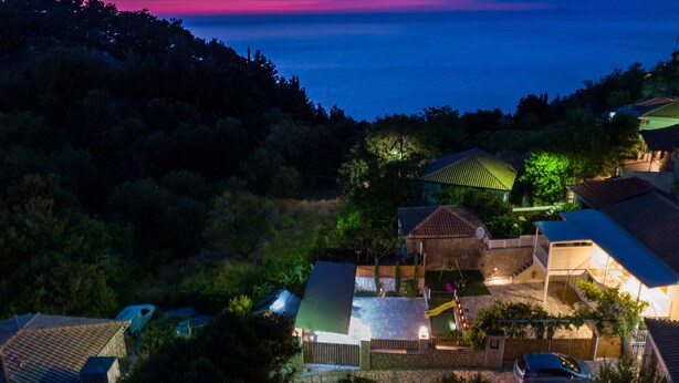 A residential area with houses, a swimming pool, and a view of the sea at dusk. - Stoned Traditional House just 3km from amazing beaches (Kalamitsi)