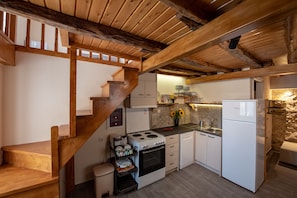 Cozy kitchen with a gas stove, oven, and refrigerator, plus a sink and white cabinets.