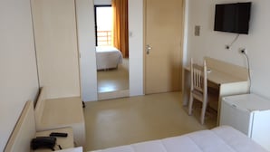 A hotel room with a bed, a desk, a chair, a TV, and a wardrobe. - Hotel Kimar (Tramandai)