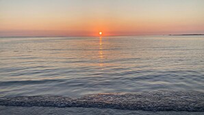 Ein ruhiges Meer bei Sonnenuntergang mit erkennbarer Horizontlinie.