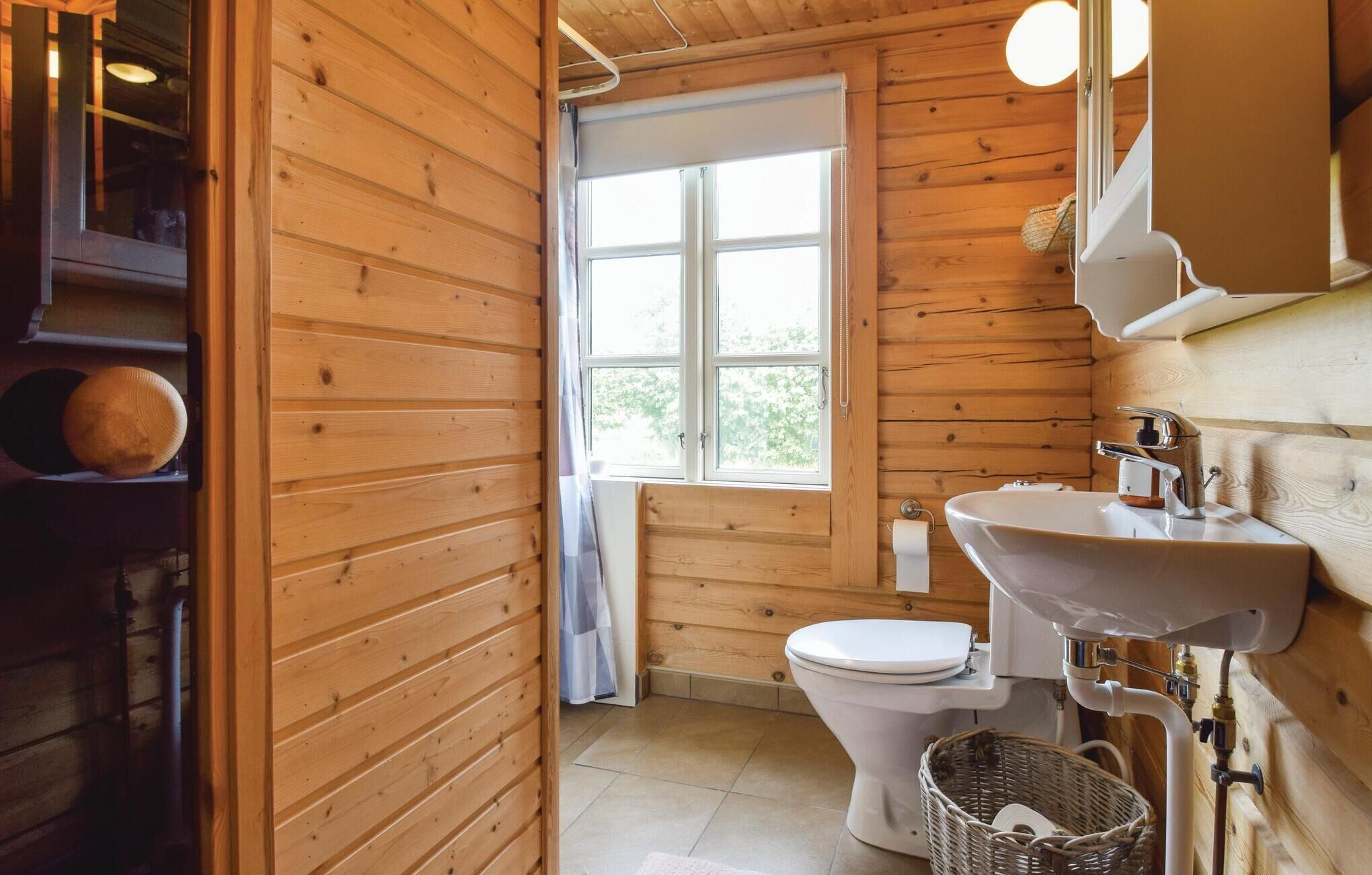 Ein Badezimmer mit Holzausstattung, das eine Toilette, ein Waschbecken und ein Fenster beinhaltet.