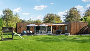 A modern outdoor patio with a dining area, lounge chairs, and a barbecue grill.