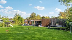 A backyard with a wooden deck, a trampoline, and a play area.