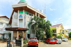Un edificio con un cartello verde riportante la scritta "GREEN ADMIYASKA" e un'auto rossa parcheggiata davanti.