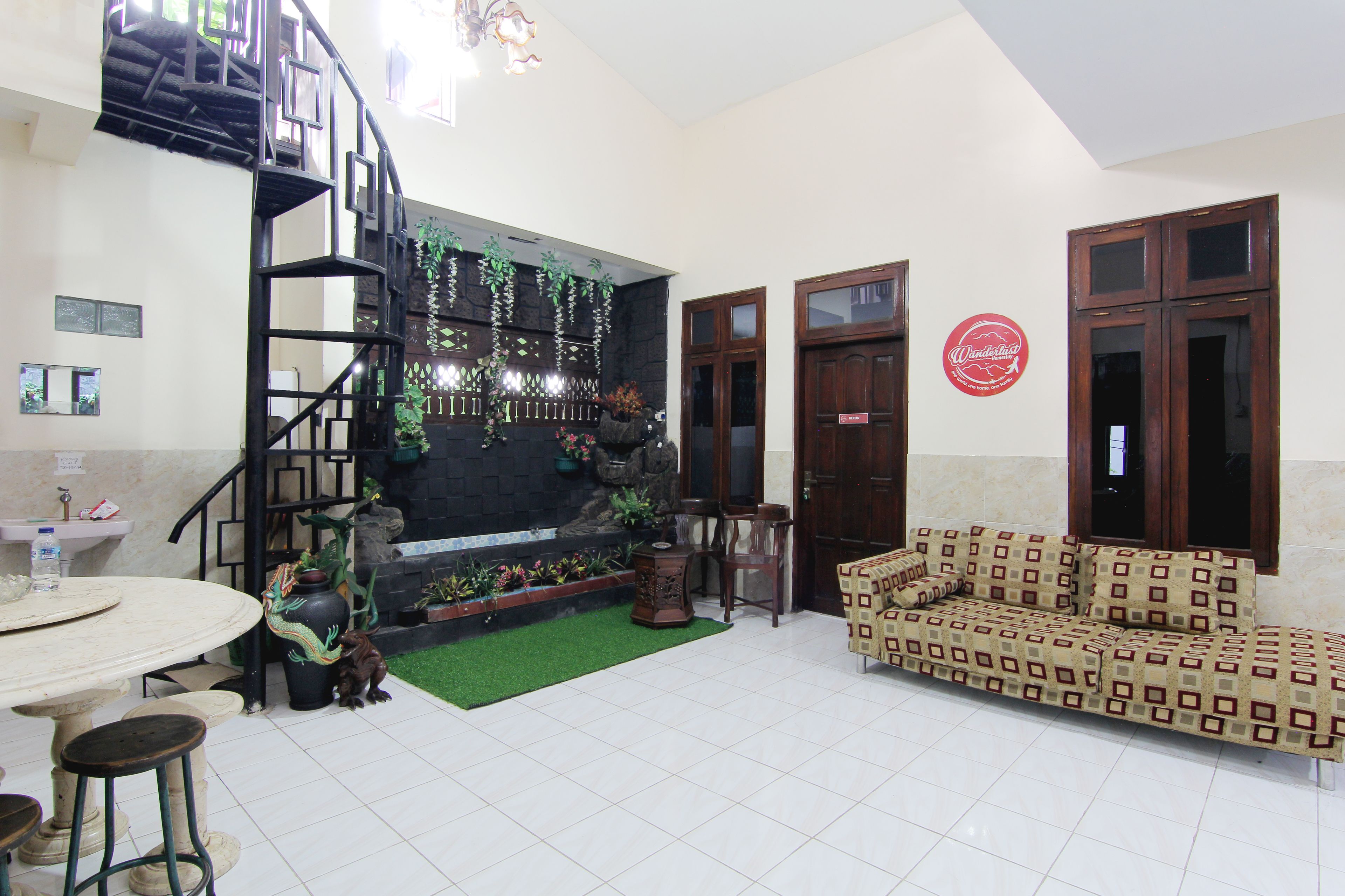 A spacious living area with a staircase, a sofa, a dining table, and a decorative wall.