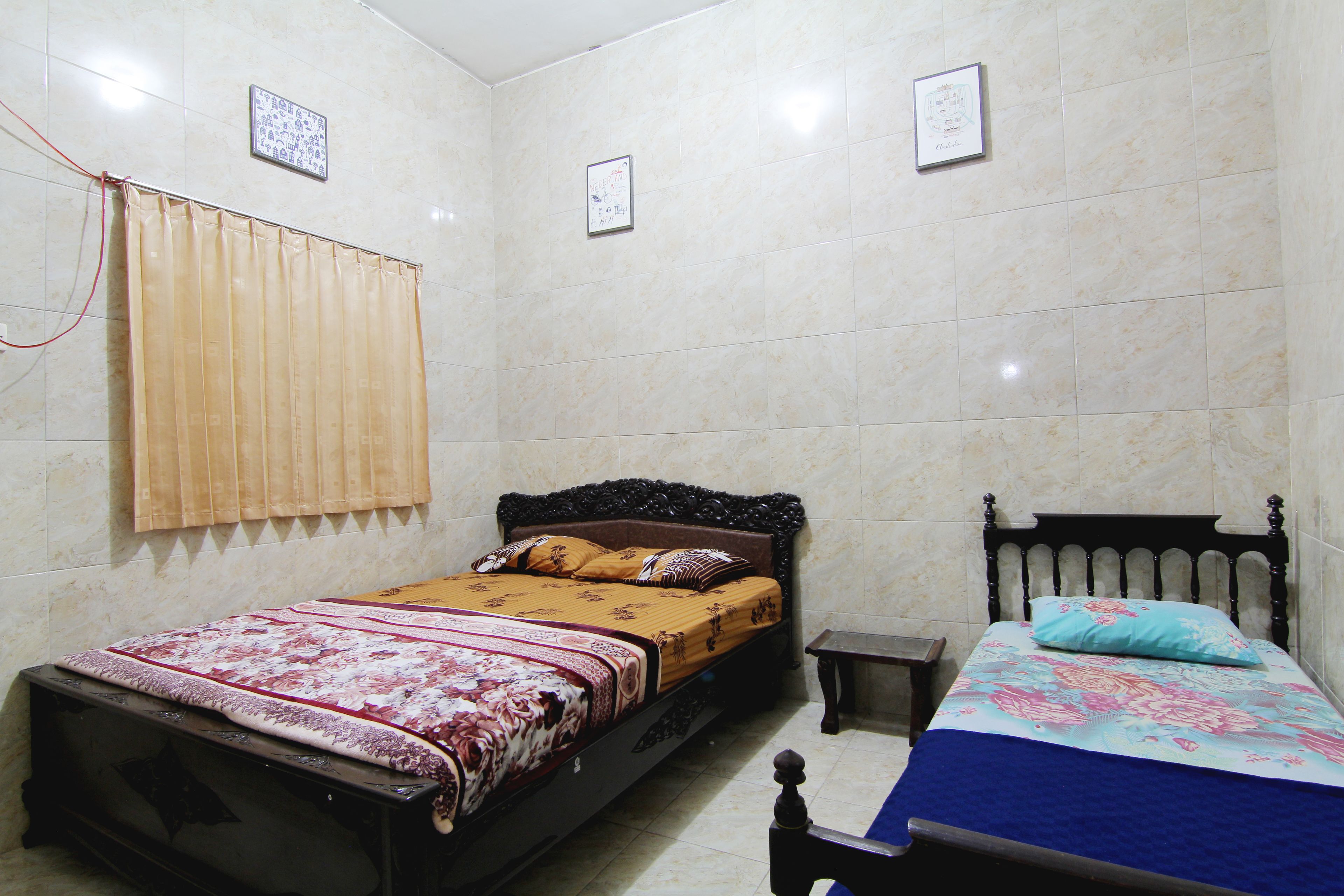 A bedroom with two beds, a wooden headboard, a nightstand, and a window with curtains.