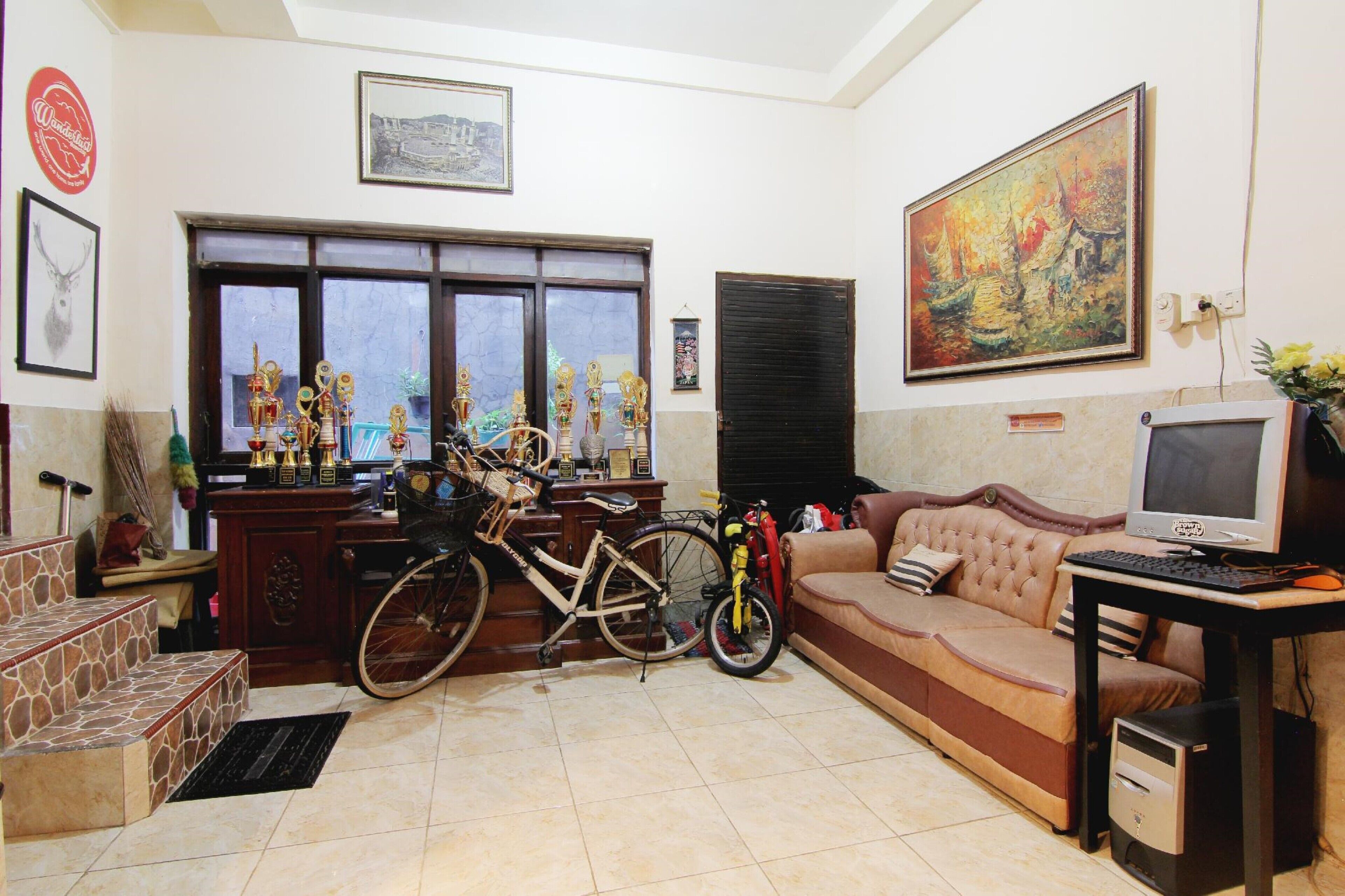 A living room with a sofa, a television, a bicycle, and trophies on a shelf.