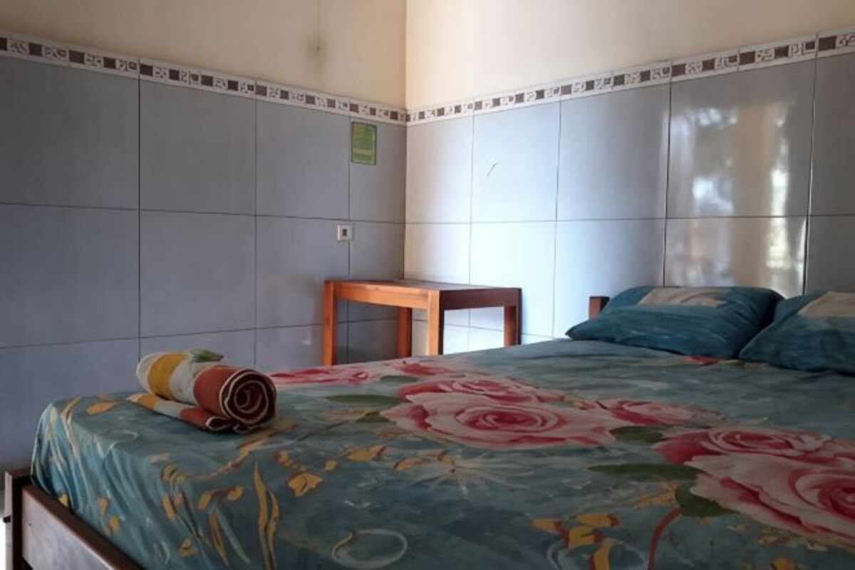 A bedroom with a bed, a wooden table, and a tiled wall.