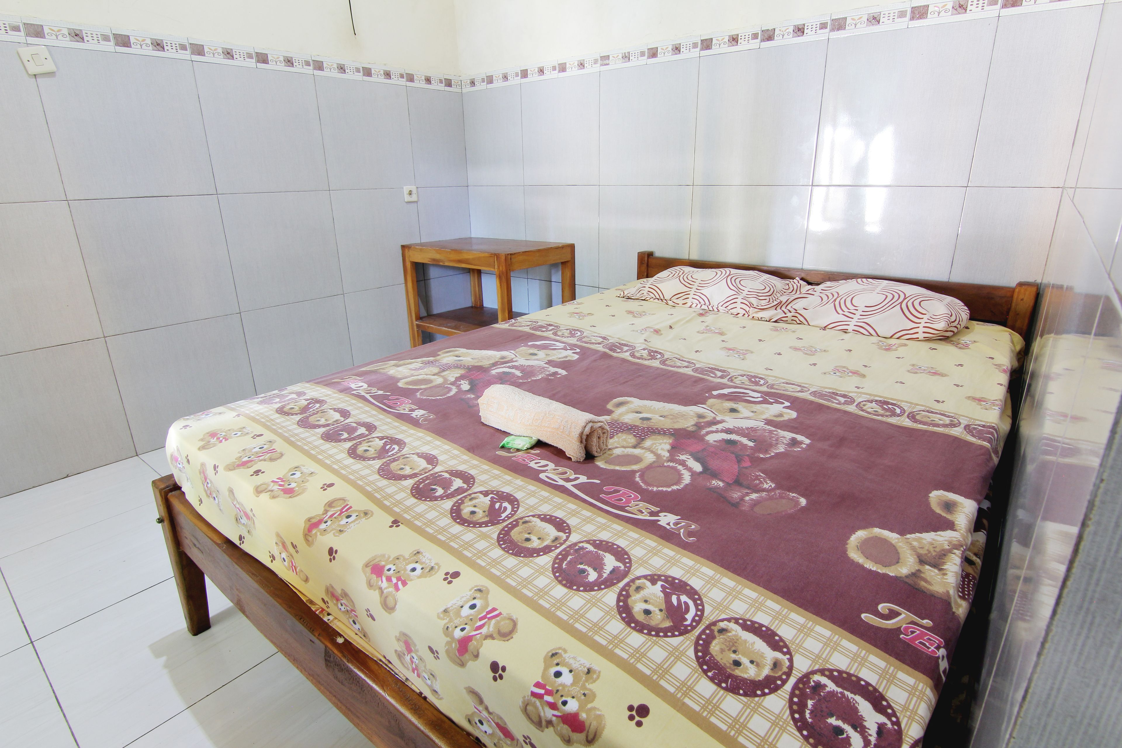 Un dormitorio con cama, mesita de noche de madera y pared de azulejos.