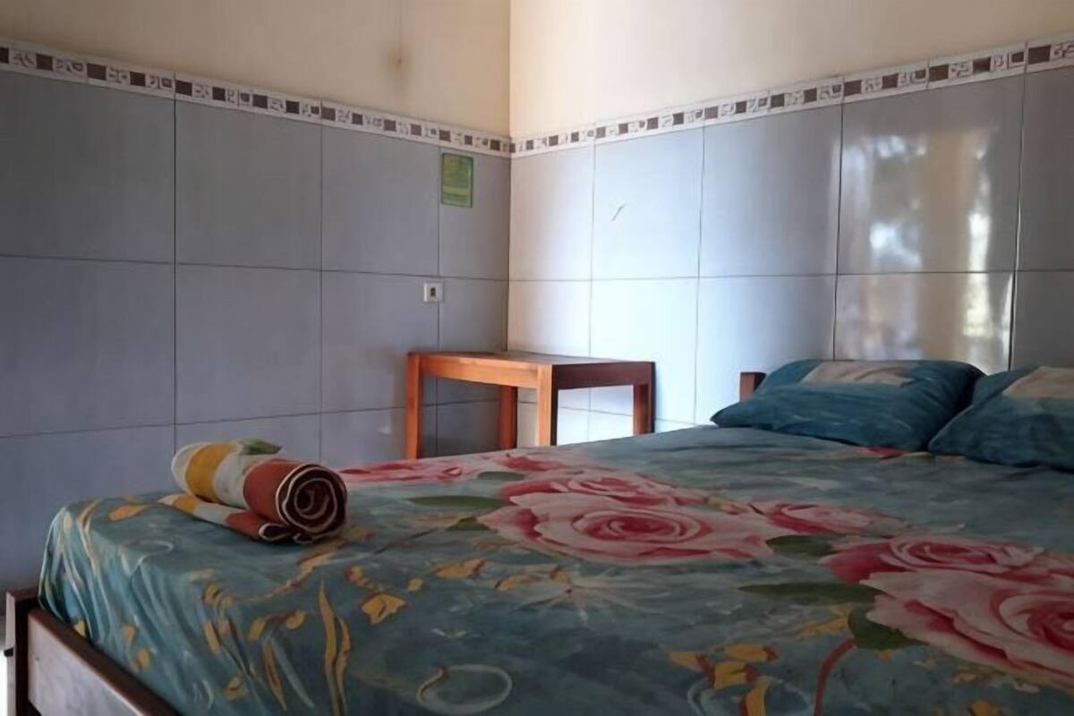 A bedroom with a bed, a wooden table, and a tiled wall.