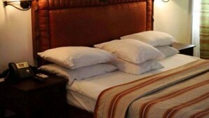 Ein Hotelzimmer mit einem großen Bett, vielen Kissen, einem Nachttisch mit Telefon und einem Kopfteil.
