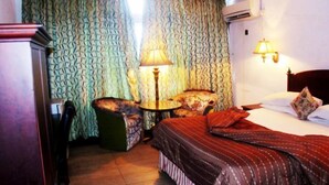 Ein Hotelzimmer mit Bett, Sessel, kleinem Tisch und Lampe.
