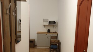 A narrow hallway with wooden flooring leading to a kitchen area with a microwave and a small cabinet. - Guest House Orczy Park (Budapest)