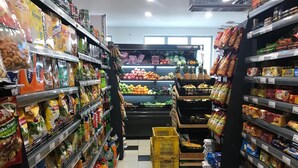 Pasillo de un supermercado con estantes llenos de aperitivos, bebidas y frutas frescas.