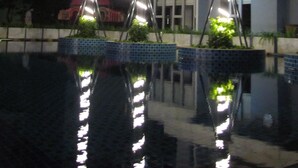 Vista nocturna de un edificio con un estanque reflectante e iluminación decorativa.