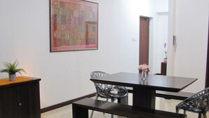 Un comedor con una mesa de madera oscura, sillas de metal y un florero decorativo con flores.