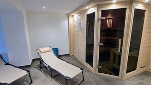 Une pièce comprenant une table de massage, un petit banc et une porte-fenêtre coulissante donnant sur un espace douche.
