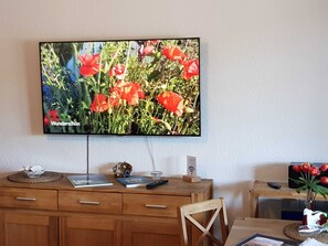 A television mounted on a wall displaying a flower scene. - Residence Seeblick 28 with lateral Baltic Sea view - Studio 28 / with balcony (Sellin)