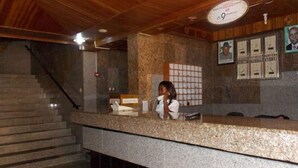 A reception desk with a counter, a staircase, and framed pictures on the wall. - Royal Paragon Hotel (Port Harcourt)