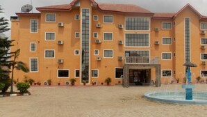 A multi-story building with a central entrance, air conditioning units, and a small fountain. - Royal Paragon Hotel (Port Harcourt)