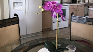 A kitchen with wooden cabinets, a white refrigerator, a microwave, and a stove. There is a table with chairs and a potted orchid. - Robin's Nest- Orlando Villa Vacation Rental. (Clermont)