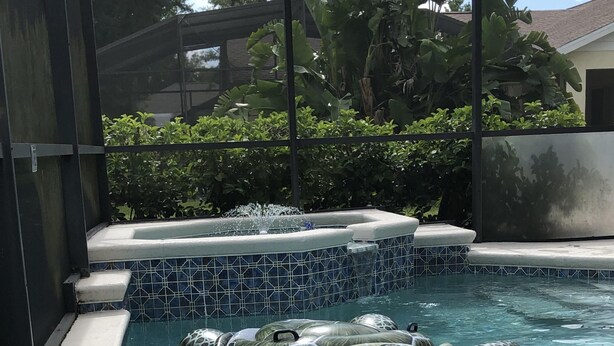 A swimming pool with clear water and a tiled edge. - Robin's Nest- Orlando Villa Vacation Rental. (Clermont)