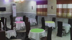 Une salle comprenant plusieurs tables rondes recouvertes de nappes blanches, disposées en cercle.