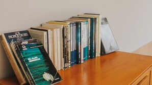 A wooden desk with a collection of books and a CD. - Hostal  Aurora - Hostel (Santa Marta)