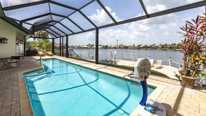 Ein überdachter Pool mit Blick auf einen See und entfernte Gebäude.